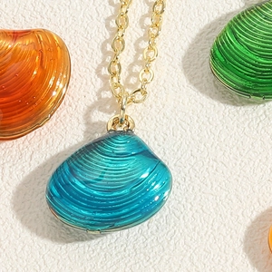 Macro-opname van de turquoise schelphanger met gouden ketting en emaille textuur