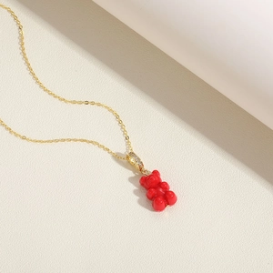 Close-up of red gummy bear resin pendant with cubic zirconia detail on gold chain