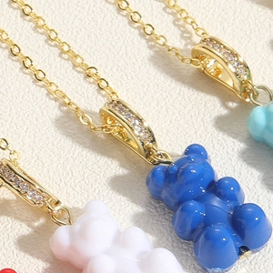 Macro shot of colorful gummy bear pendants with gold cubic zirconia rings on leather background