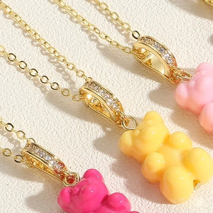 Detailed close-up of colorful resin gummy bear pendants with zircon-encrusted gold bails