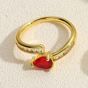 Detailed macro view of pear-cut red gemstone on gold belt buckle ring with zircons