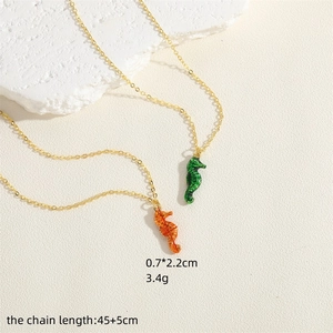 Colorful enamel seahorse pendant necklace on white textured stone background with gold chain