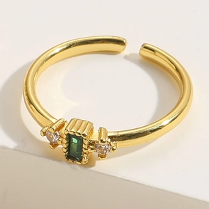 Macro d'une bague dorée ajustable avec émeraude rectangulaire et pierres de zircon