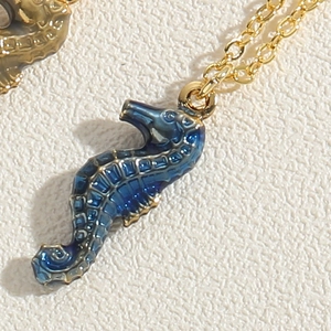 Macro view of blue enamel seahorse pendant with golden scales and delicate chain