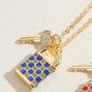Vue macro d'un collier doré avec pendentif serrure à damier bleu et clé en cœur