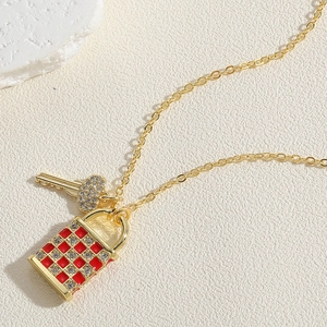 Vue macro du pendentif serrure et clé en or avec émail rouge à damier et zircons