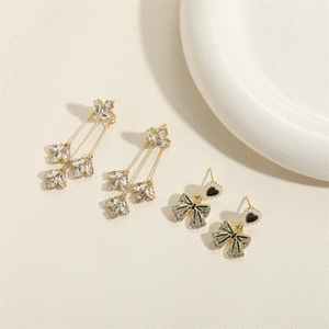 Elegantes Set aus goldenen Ohrringen mit Kristallblättern und schwarzen Herz-Schleifen