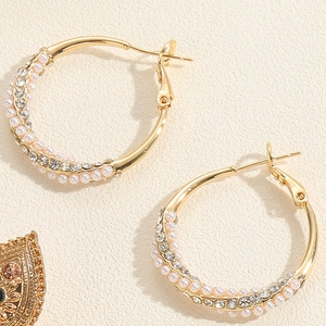 Vue détaillée de créoles vintage dorées avec perles blanches et strass étincelants