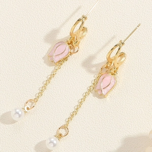 Macro de boucles d'oreilles tulipes roses avec chaîne dorée et perles blanches