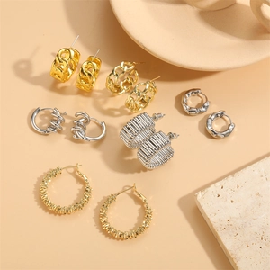 Set di sei orecchini a cerchio grossi oro e argento stile catena cubana su sfondo minimal