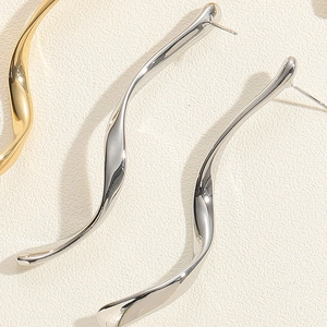 Detailed macro view of long wavy metallic earrings with a high-polished mirror finish