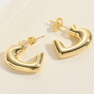 Macro detail of polished gold C-shaped heart stud earrings with butterfly backing