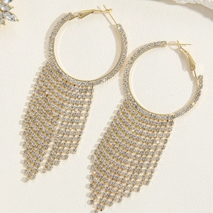 Dettaglio di orecchini dorati con nappe di strass brillanti e design a cerchio allungato