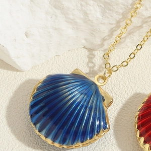 Macro shot of deep blue enamel shell pendant on a gold chain necklace jewelry piece