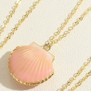 Macro view of pink enamel scallop shell pendant with golden metallic edges