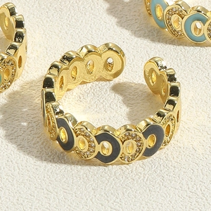 Close-up of golden adjustable ring with colorful enamel oval patterns and zircons