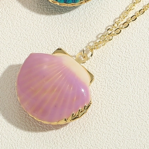 Macro shot of purple gradient scallop shell locket pendant on a gold cross chain