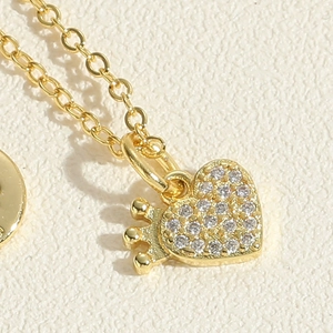 Dettaglio macro del ciondolo a cuore dorato con corona e zirconi incastonati