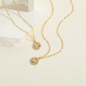 Macro view of gold necklaces with zircon-set zodiac pendants on white textured stone