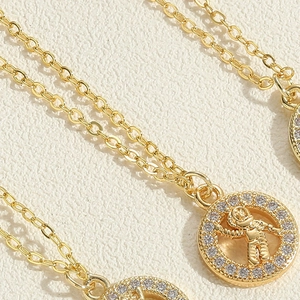 Macro detail of gold astronaut pendant necklace with sparkling cubic zirconia pavé