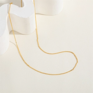 Detail of a thin gold-plated O-link chain necklace on a white artistic display stand