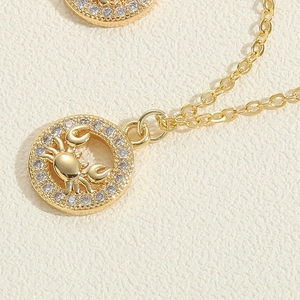 Macro detail of a gold Cancer zodiac necklace featuring a crab pendant with zircon stones
