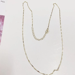 Detailed close-up of golden bar link necklace with lobster clasp and extension chain