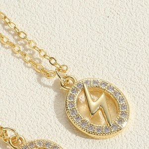 Close-up of golden oval lightning bolt pendant with white zircon inlay on cross chain