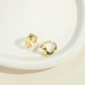 Minimalistische goldene Metallringe mit quadratischem Niet und Wellendesign auf Tablett