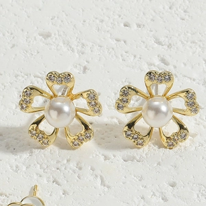 Macro view of gold flower stud earrings with central pearl and sparkling zircon petals
