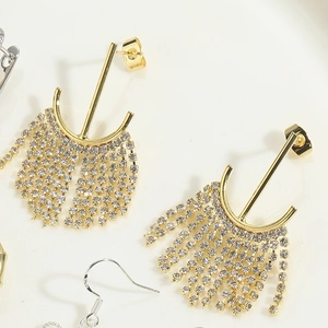 Vue macro de boucles d'oreilles dorées en forme de bambou avec franges en strass