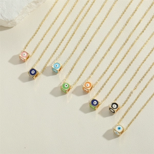 Gold necklaces featuring colorful cube pendants with evil eye designs on textured background