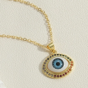 Close-up of golden evil eye pendant necklace with rainbow zircon stones and blue pupil