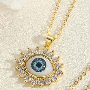 Close-up detail of golden evil eye pendant necklace with blue eye and white zircon inlay