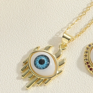 Macro shot of evil eye pendant with blue zircon and golden eyelashes on a fine link chain