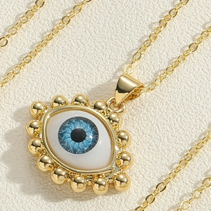 Macro detail of the evil eye pendant with blue resin and golden bead embellishments