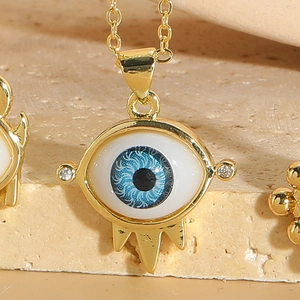 Macro detail of gold evil eye pendant necklace with zircon accents and spikes