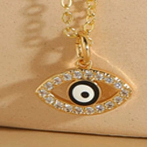 Dettaglio macro della collana con ciondolo malocchio dorato, cristalli e smalto