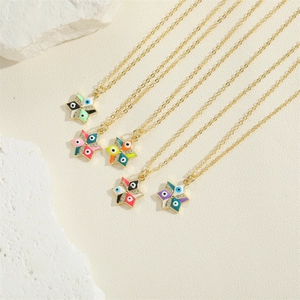 Golden star evil eye necklaces with colorful enamel pendants on a textured stone background