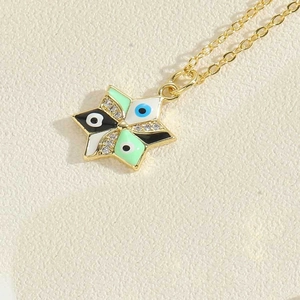 Detailed close-up of golden star pendant necklace with colorful enamel evil eye and zircons