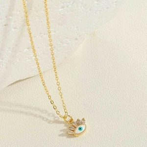 Détail du collier pendentif œil maléfique avec cils en zircone sur fond de pierre