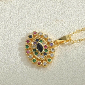 Detailansicht eines goldenen Evil-Eye-Anhängers mit bunten Zirkoniasteinen und Edelstein