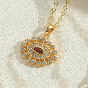 Makroaufnahme der goldenen Evil Eye Halskette mit rotem Edelstein und Mikro-Pavé-Kristallen