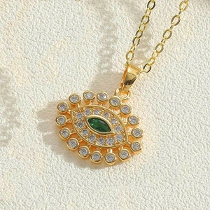 Makroansicht der goldenen Evil-Eye-Kette mit grünem Stein und Zirkonia-Besatz