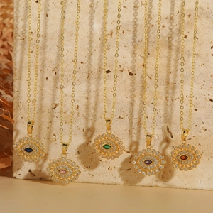 Goldene Evil Eye Anhänger Halsketten mit bunten Kristallsteinen auf Natursteinhintergrund