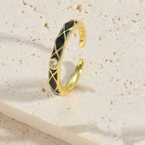 Macro-opname van vergulde ring met zwart emaille ruitpatroon en glanzende zirkoon