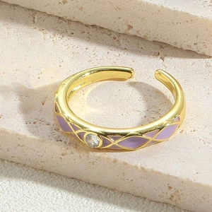 Macro-opname van vergulde ring met paarse emaille patronen en een fonkelende zirkoon