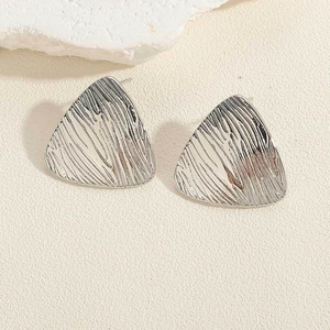 Detail view of silver triangle stud earrings featuring irregular textured metal surface