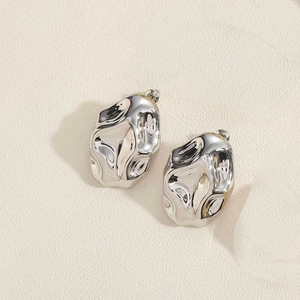 Detail of silver triangle stud earrings with molten metal texture and modern art finish