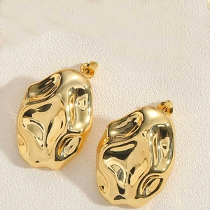 Detailed macro view of 14K gold plated triangular earrings with textured lava pattern